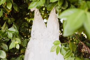 Sleeveless lace wedding dress hung among green leaves